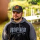 person wearing black and yellow rapala late 80s rope hat near a dock