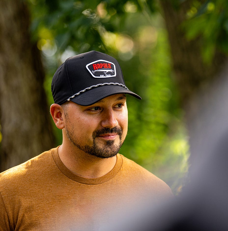 person wearing white and black late 80s rapala rope hat in the woods